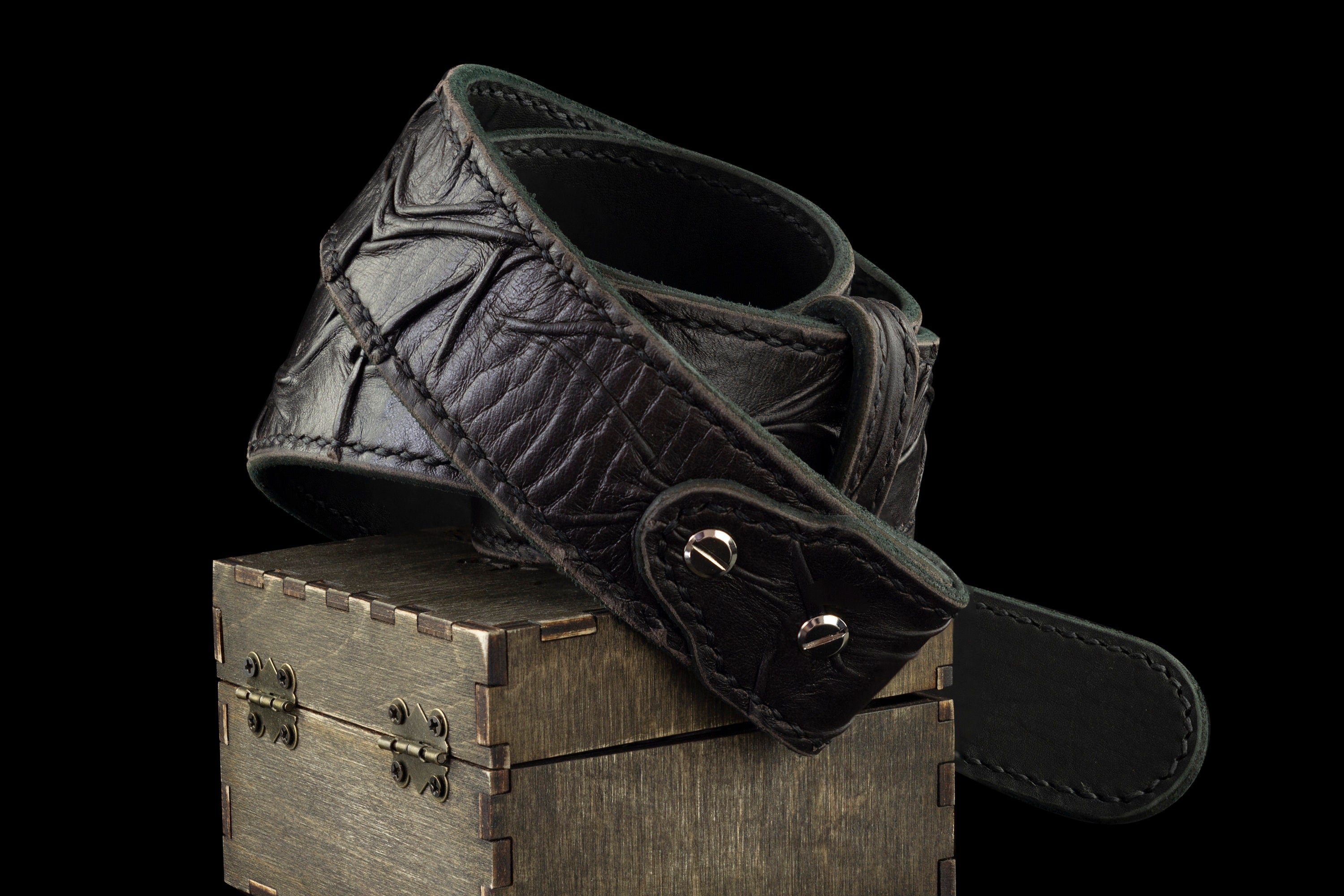 Rock Road leather belt strap draped over a wooden box, showing the buckle end