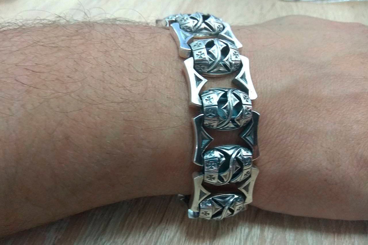 Heavy Maltese cross silver bracelet worn on a man's wrist
