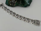 Close-up of oxidized Maltese cross links in relief on the heavy silver bracelet