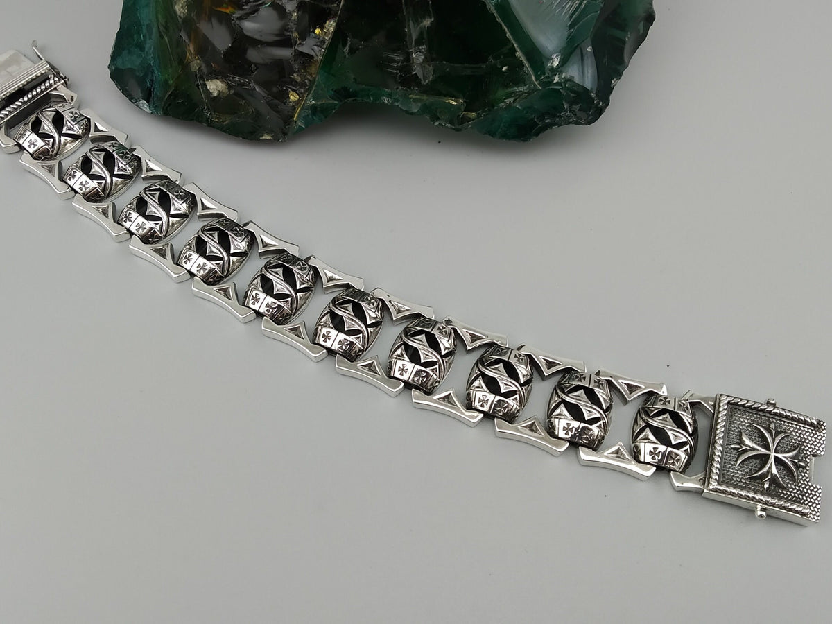Close-up of oxidized Maltese cross links in relief on the heavy silver bracelet