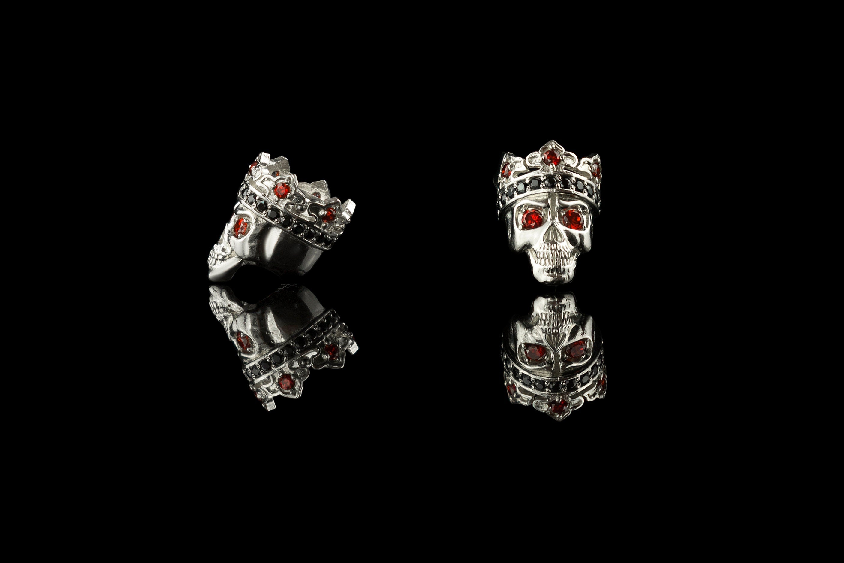 Santa Muerte skull charm bead shown from the front and side, red and black stones in the crown