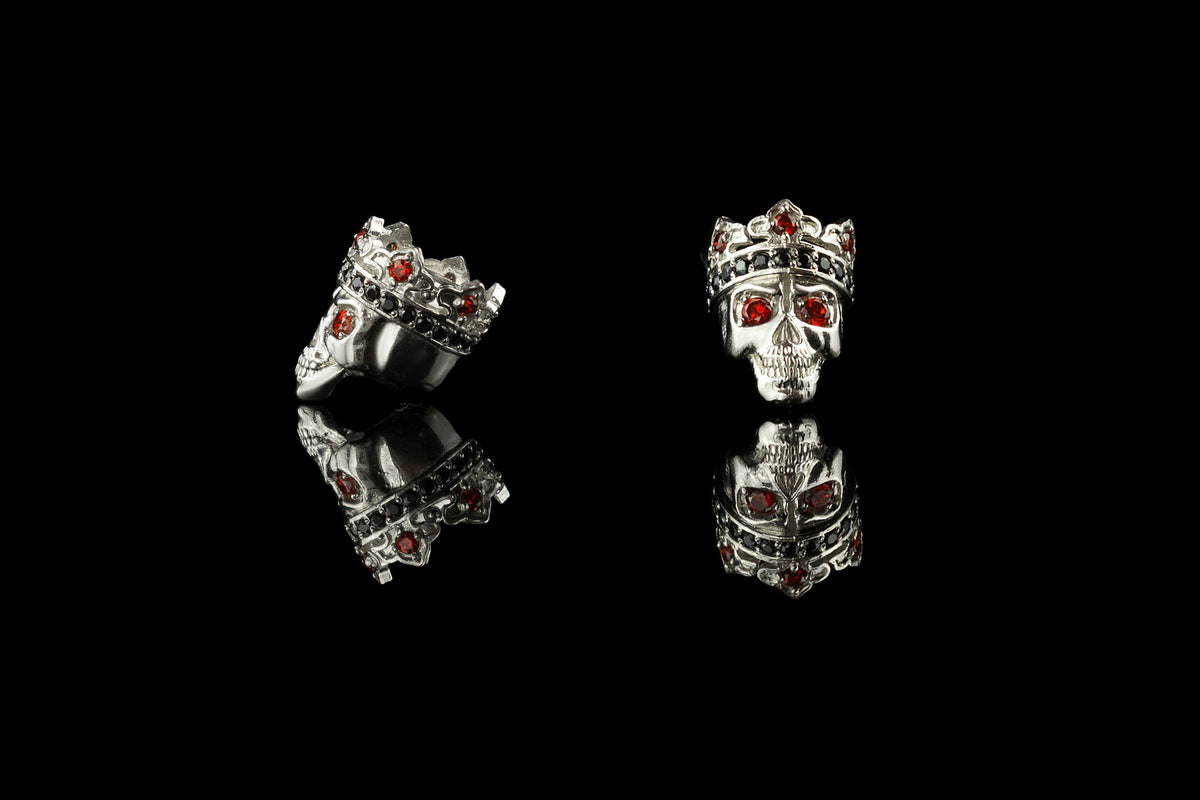 Santa Muerte skull charm bead shown from the front and side, red and black stones in the crown
