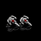Pair of sterling silver scorpion stud earrings with red cubic zirconia on a black background