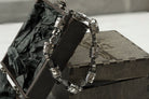 Skull piston heavy silver biker bracelet draped over a wooden box
