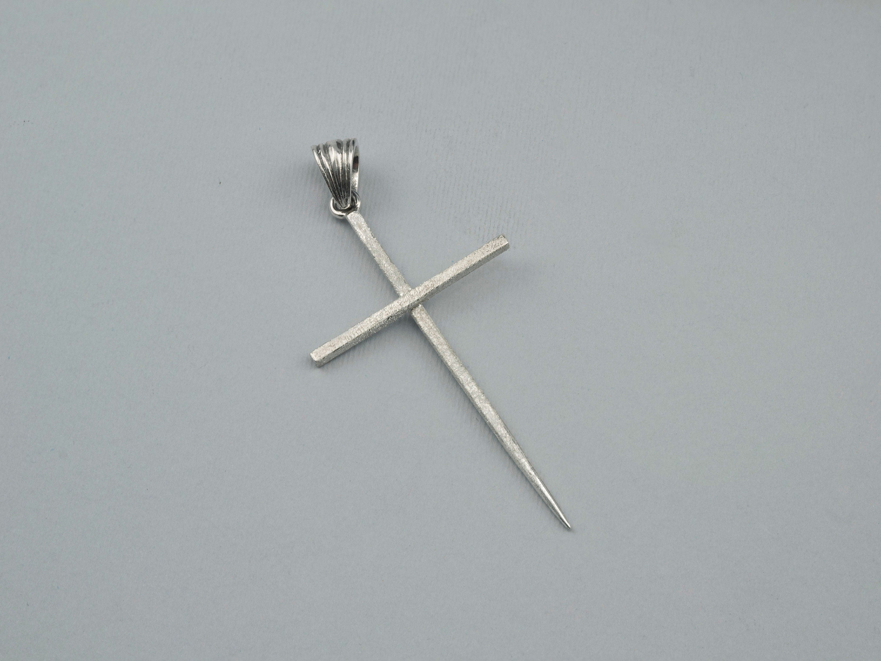 Spike cross pendant angled view showing the slim elongated arms
