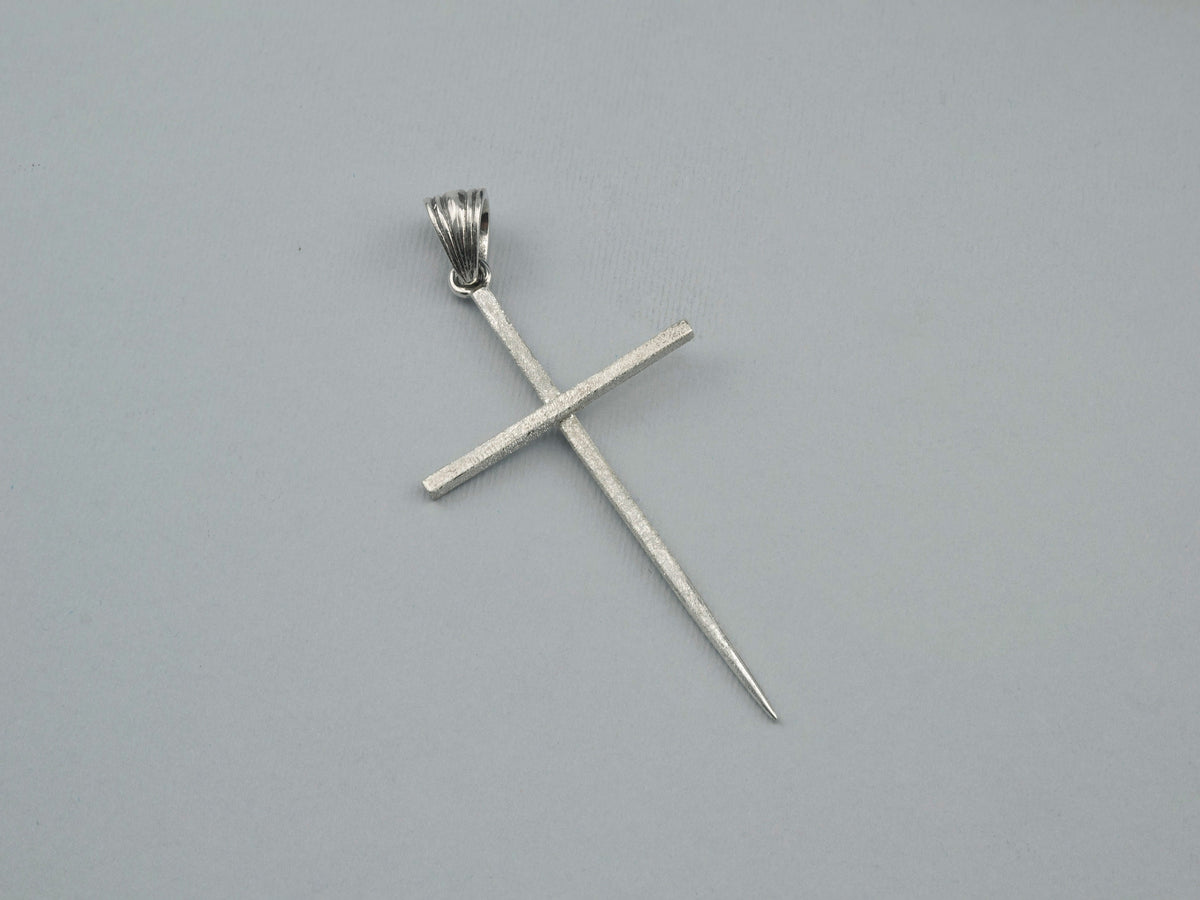 Spike cross pendant angled view showing the slim elongated arms