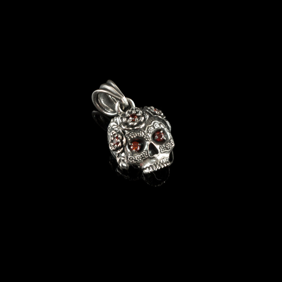 Tiny Frida sterling silver floral skull pendant with red stone eyes, front closeup