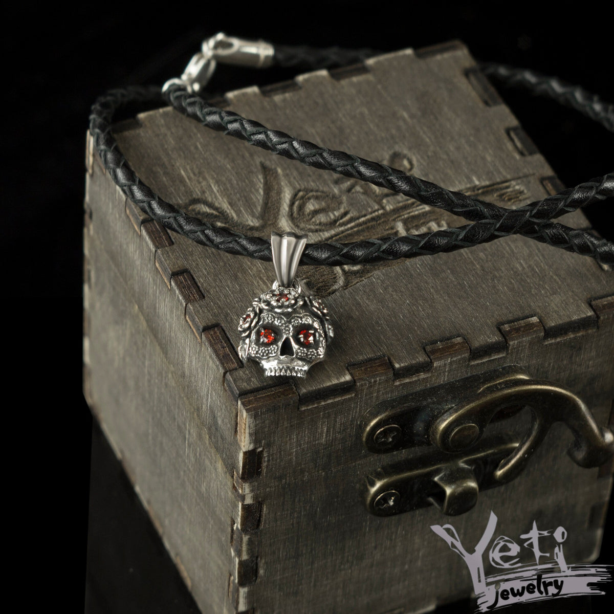 Tiny Frida sterling silver floral skull pendant with red stone eyes, on cord box