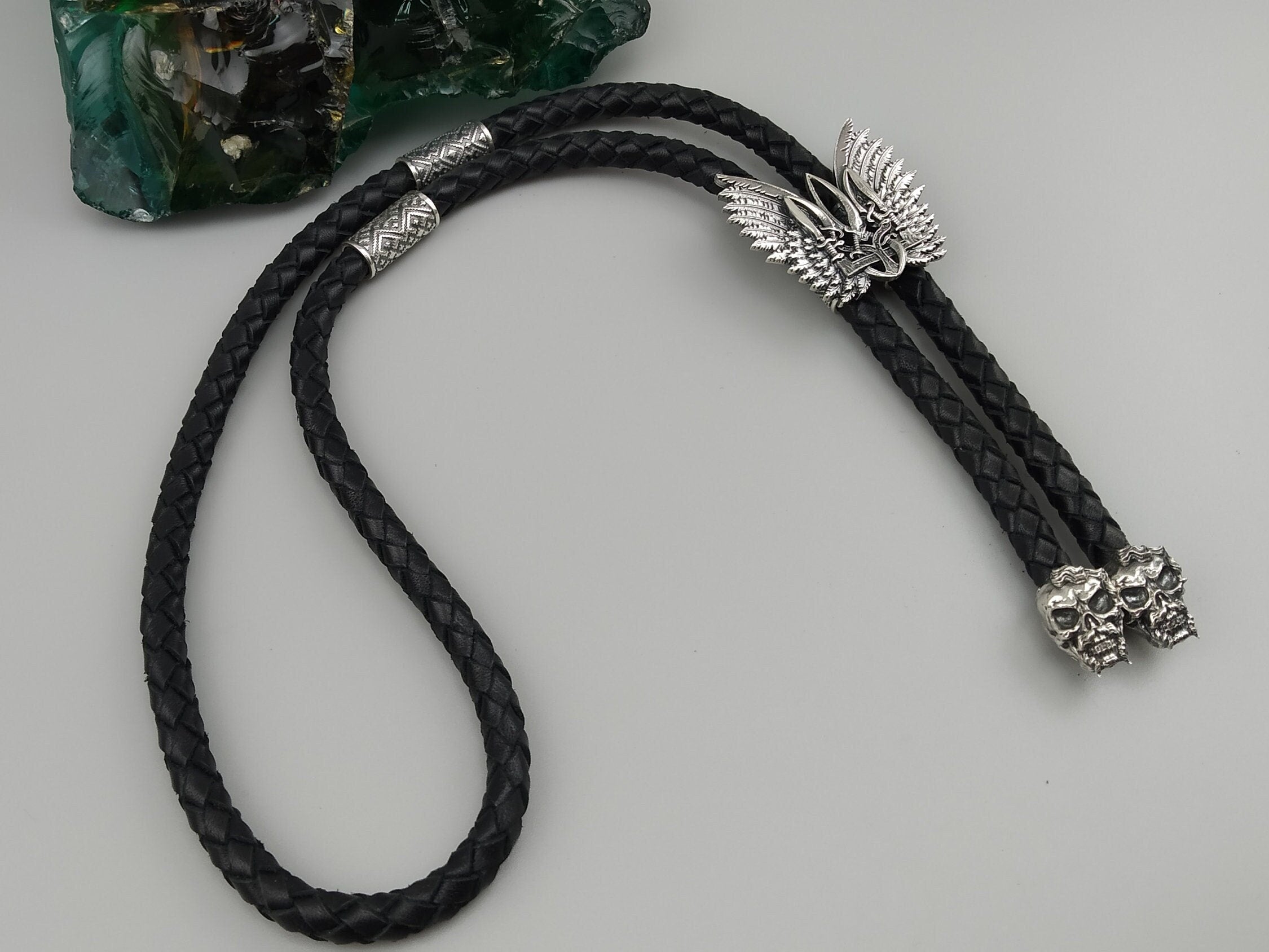 Sterling silver Tryzub bolo tie laid flat, showing winged slide, patterned bead and skull ends