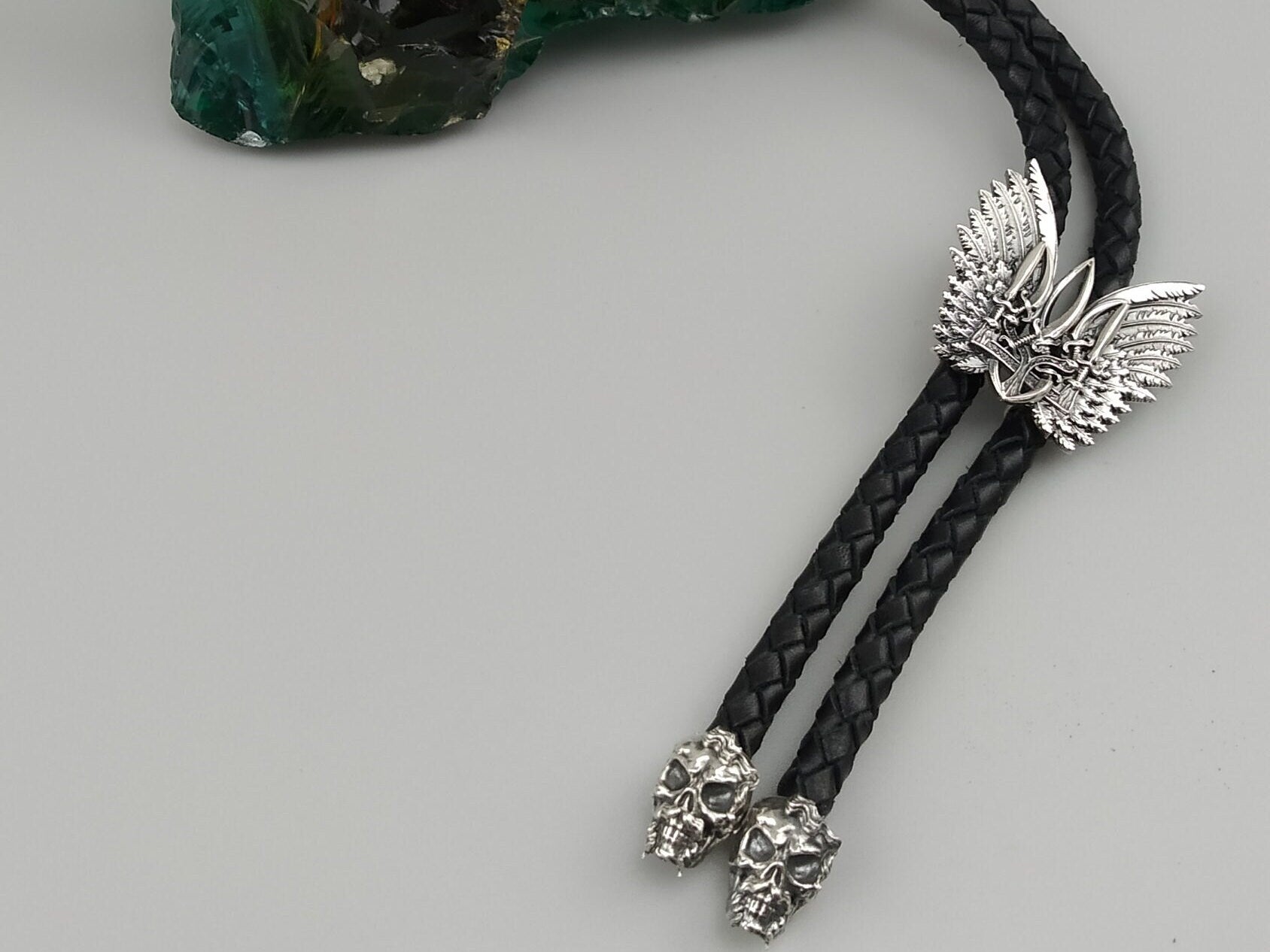 Close-up of the winged Tryzub slide and two sculpted silver skull tips of the bolo tie