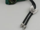 Close-up of the winged Tryzub slide and two sculpted silver skull tips of the bolo tie