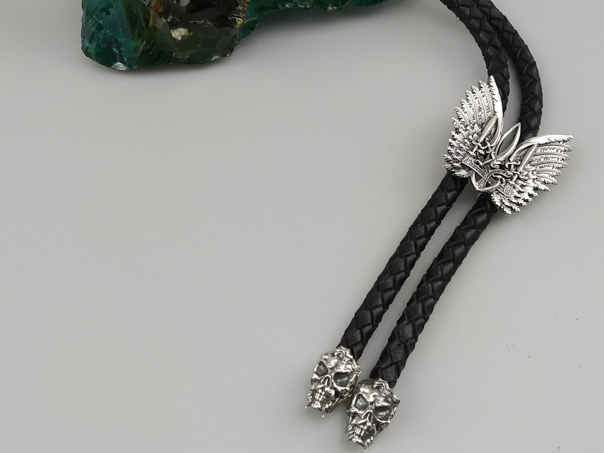 Close-up of the winged Tryzub slide and two sculpted silver skull tips of the bolo tie