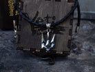 Tryzub pendant on a cord over a wooden gift box, front view