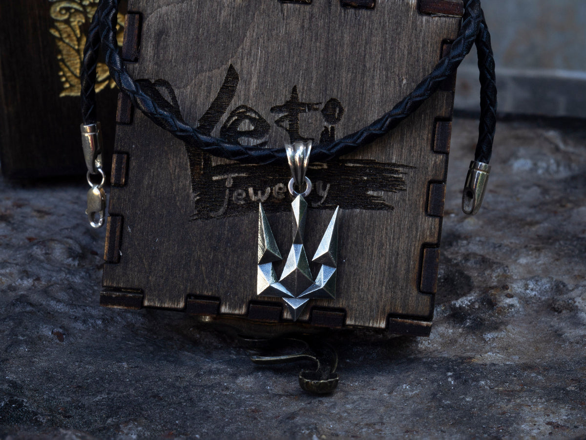 Tryzub pendant on a cord over a wooden gift box, front view