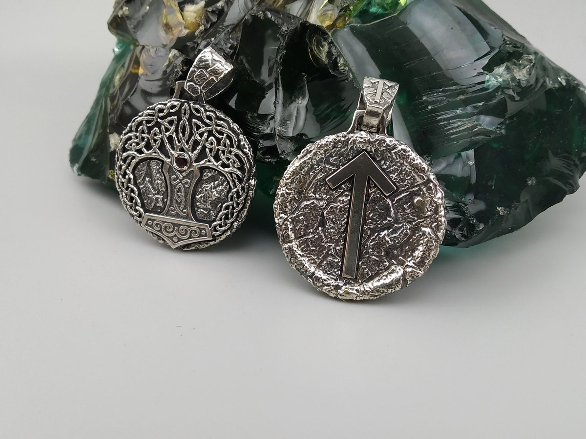 Yggdrasil pendant next to a round Tiwaz rune pendant in sterling silver